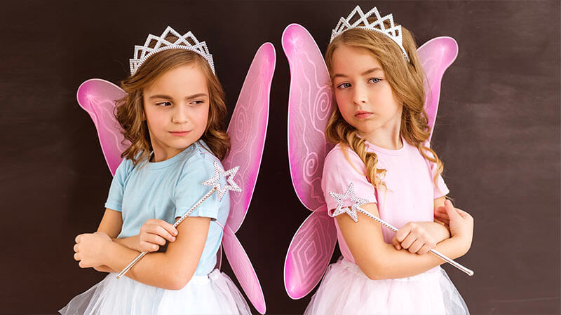 image shows two young girls dressed as fairies with their arms crossed and their backs to one another looking angry